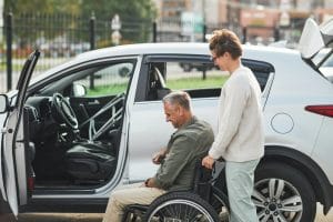 Couple with Man in Wheelchair by Car Side View
