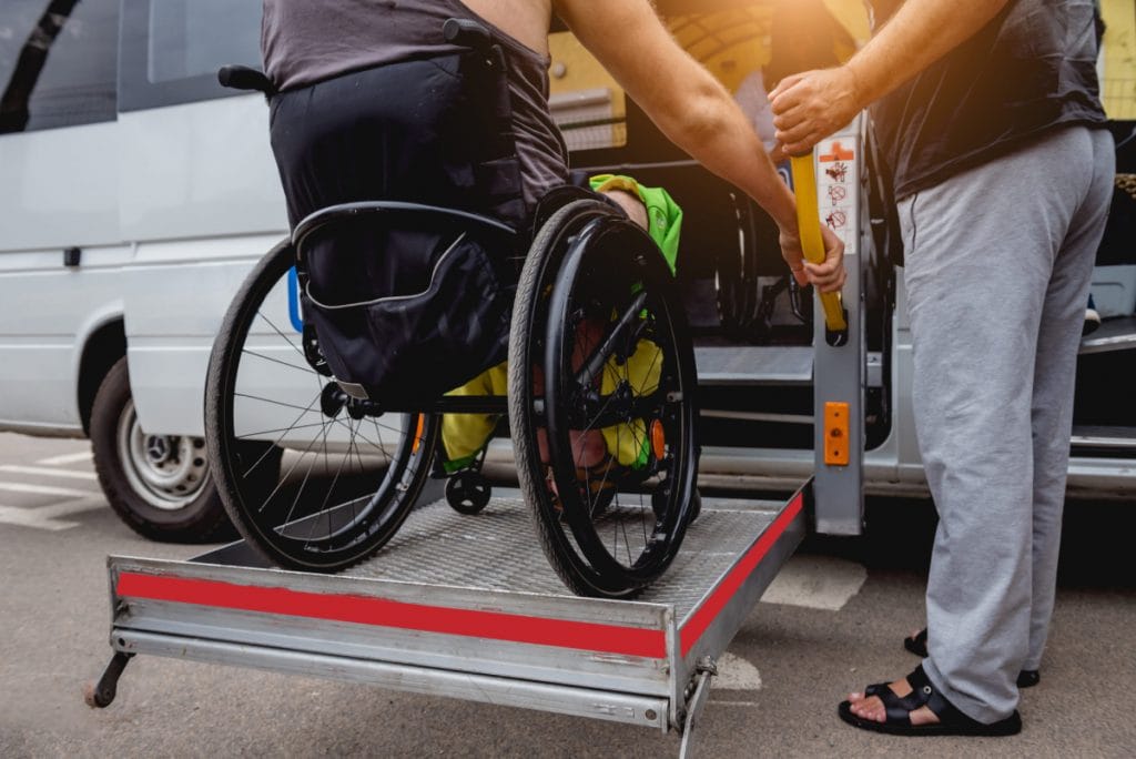 A man with a wheelchair is boarding a bus.
