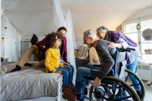 Happy multiethnic diverse family enjoying weekend together at home. Senior people with wheelchair.