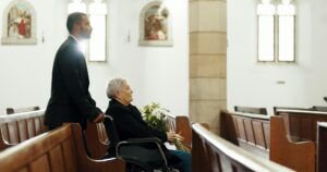 Sad, funeral and church with old woman and wheelchair user for death, mourning and widow. Depressio