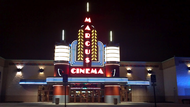 Neon-lit exterior of a cinema at night with "Marcus Cinema" prominently displayed.