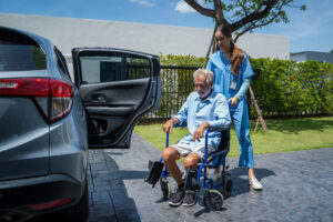 A personal care assistant assists an elderly man in a wheelchair.