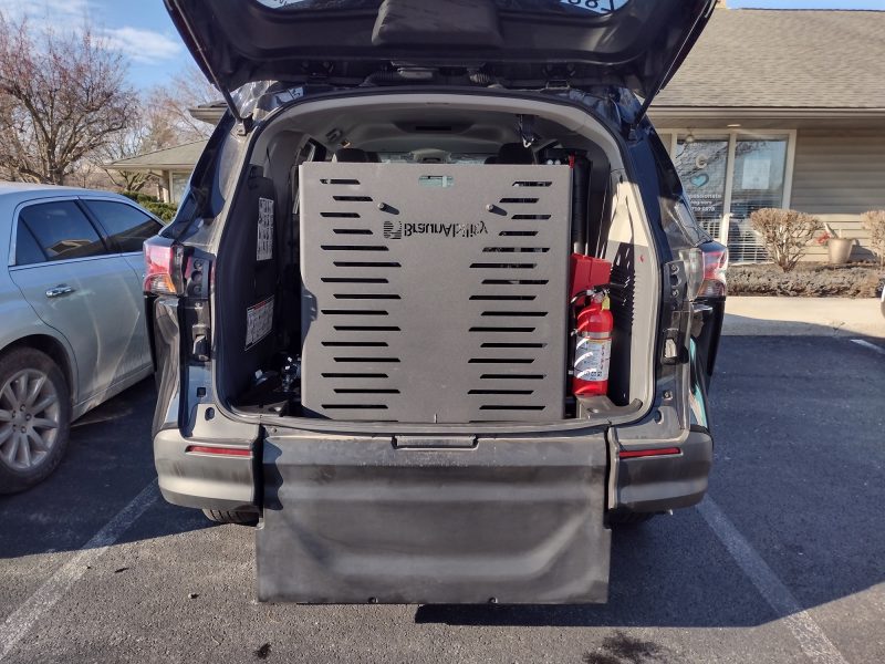 An open vehicle trunk reveals a large black metal vending machine and a red fire extinguisher inside, ready for secure transport as part of our comprehensive wheelchair transportation services.