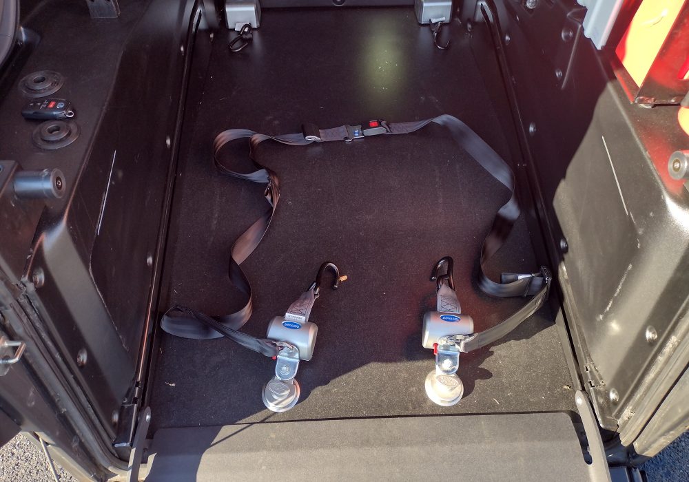 Interior of a vehicle equipped with a securement system for wheelchair users, featuring straps and anchor points on the floor. Ideal for those seeking reliable wheelchair transportation services near me, ensuring safety and comfort during transit.